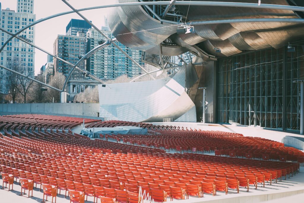 Futuristic outdoor amphitheater featuring red seats and glass panels in an urban setting.