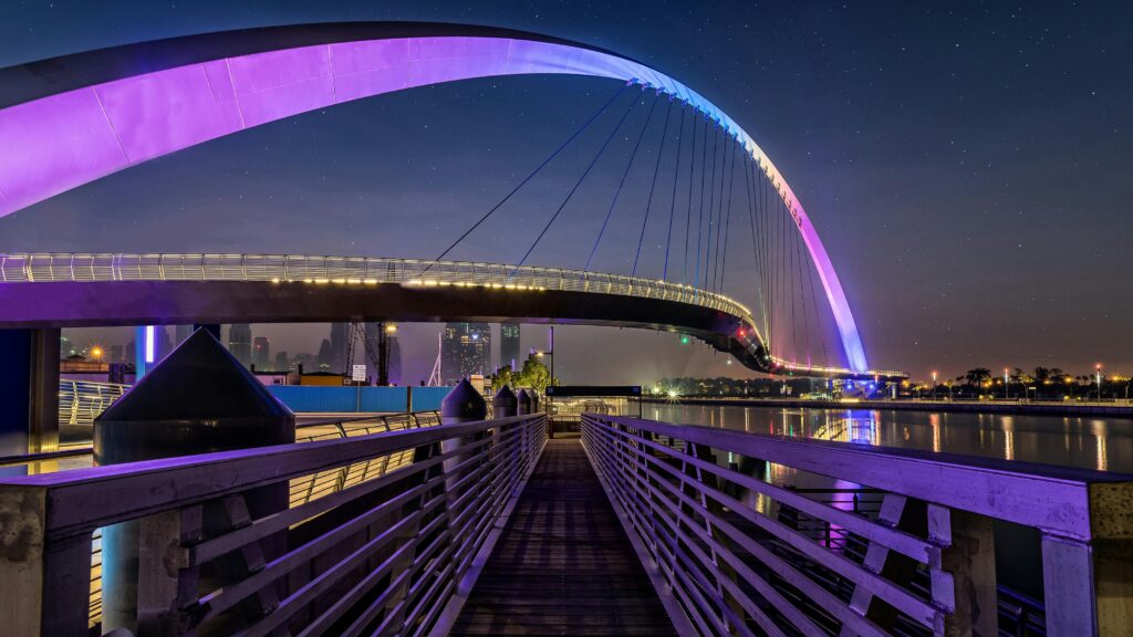 Stunning view of a modern bridge in Dubai, UAE, illuminated at night with reflections on the water.